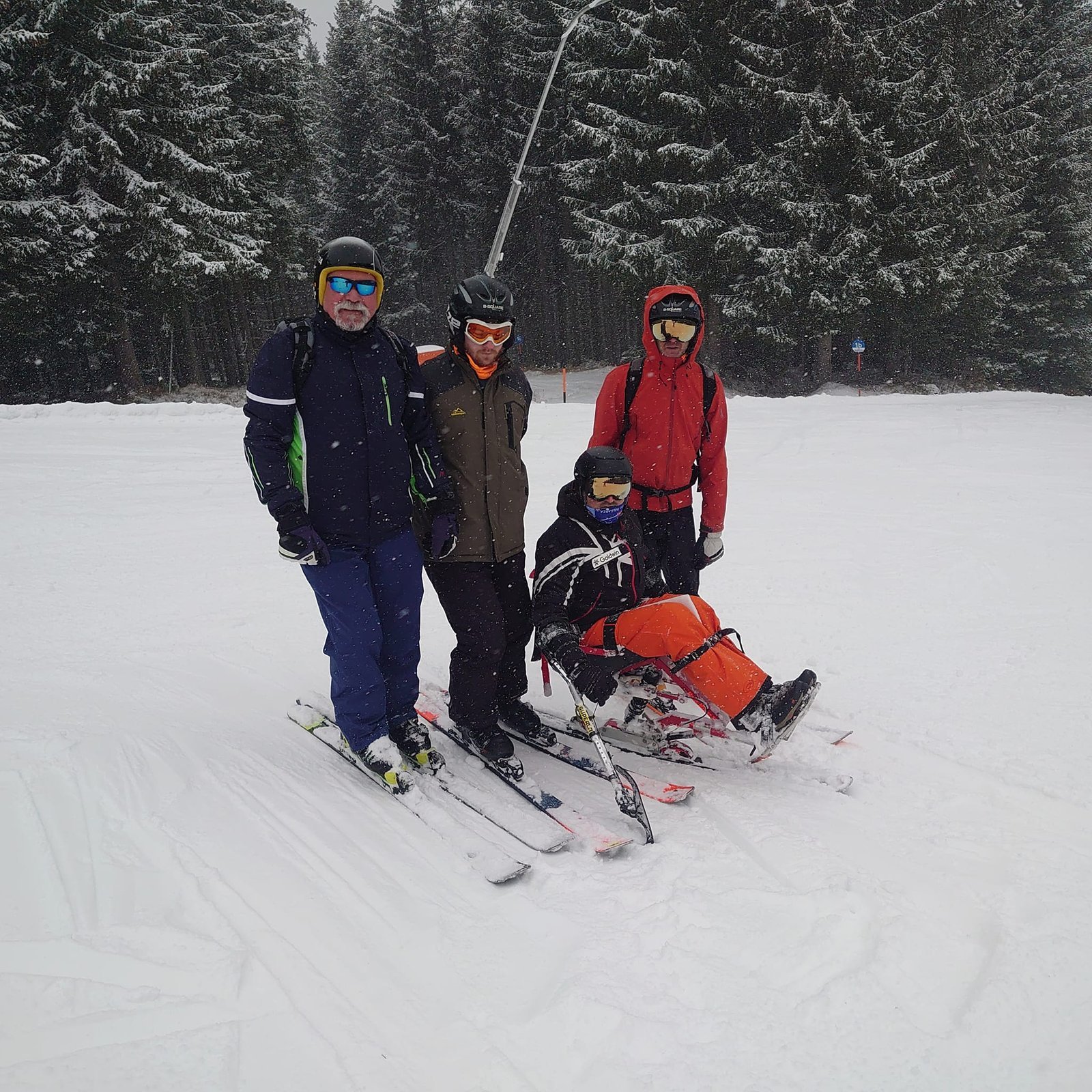 A Peel adaptive skier with three buddies on a snowy slope